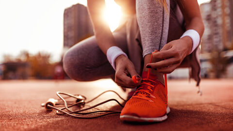 Frau bereitet sich auf Sport vor und bindet sich die Schuhe