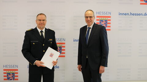 Malte Neutzler (links) gemeinsam mit Innenminister Beuth (rechts) bei der Übergabe der Urkunde, beide stehen nebeneinander und schauen in die Kamera.
