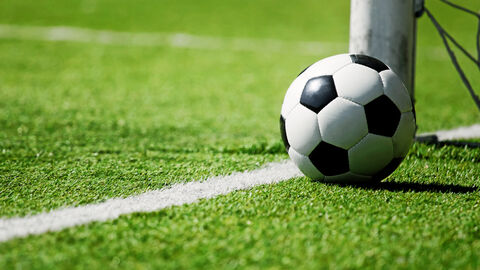 Ein Fußball liegt auf dem Fußballfeld neben dem Torpfosten.