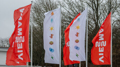 Orangene und weiße Flaggen mit Aufschrift "Viessmann" an Fahnenstangen.