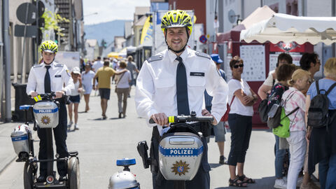 Eine Polizistin (links) sowie ein Polizist (Mitte) jeweils auf einem Segway unterwegs auf dem Hessentag 2023