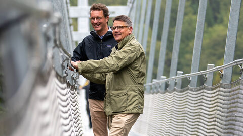 Hessens Ministerpräsident Boris Rhein (vorne) und Nordrhein-Westfalens Ministerpräsident Hendrik Wüst (hinten) in der Nähe von Willingen auf der längsten Hängebrücke Deutschlands, dem „Skywalk“
