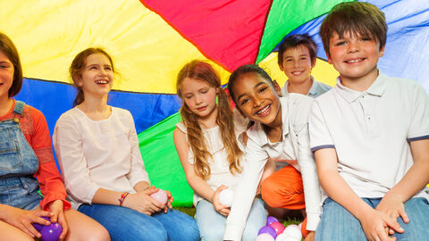 Eine Gruppe Kinder sitzt unter einem bunten Tuch
