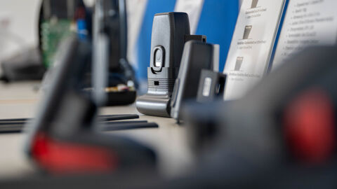 Eine elektronische Fußfessel liegt vor einem erklärenden Aufsteller.