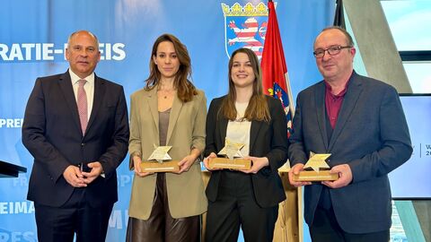 Innenminister Poseck steht mit den Preisträgern zum Gruppenfoto aufgestellt. Sie halten ihre Auszeichnungen in Händen.