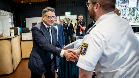 Ministerpräsident Boris Rhein schüttlt die Hand eines Polizisten. 
