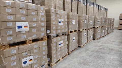 Europaletten voller Hilfsgüter stehen in einer Lagerhalle.