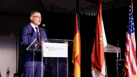 Ministerpräsident Rhein steht auf der Bühne und spricht in ein Mikofron