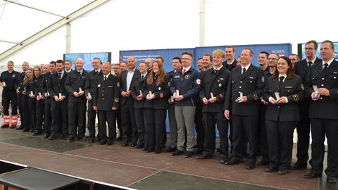 Innenminister Poseck steht mit einer großen Gruppen an Einsatzkräften auf einer Bühne